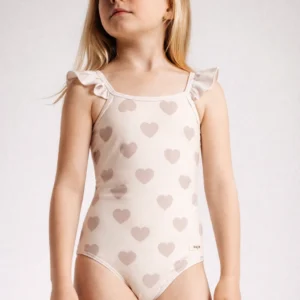 Meisje speelt met zand op strand badpak hartjes creme baje