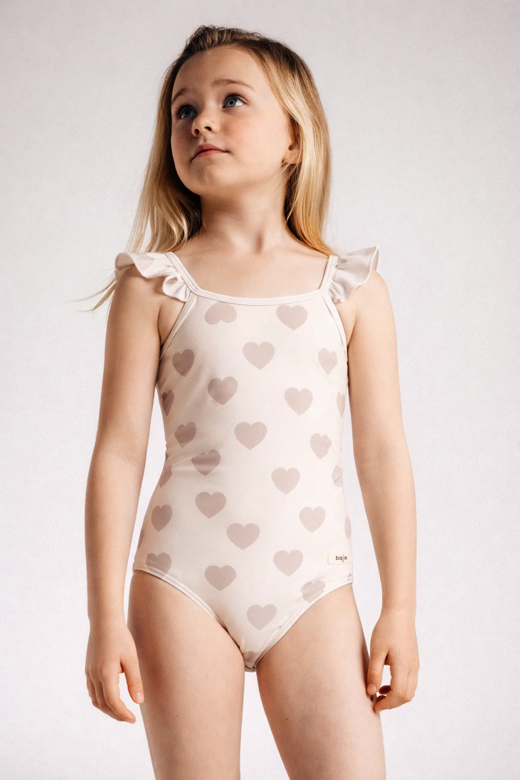 Meisje speelt met zand op strand badpak hartjes creme baje