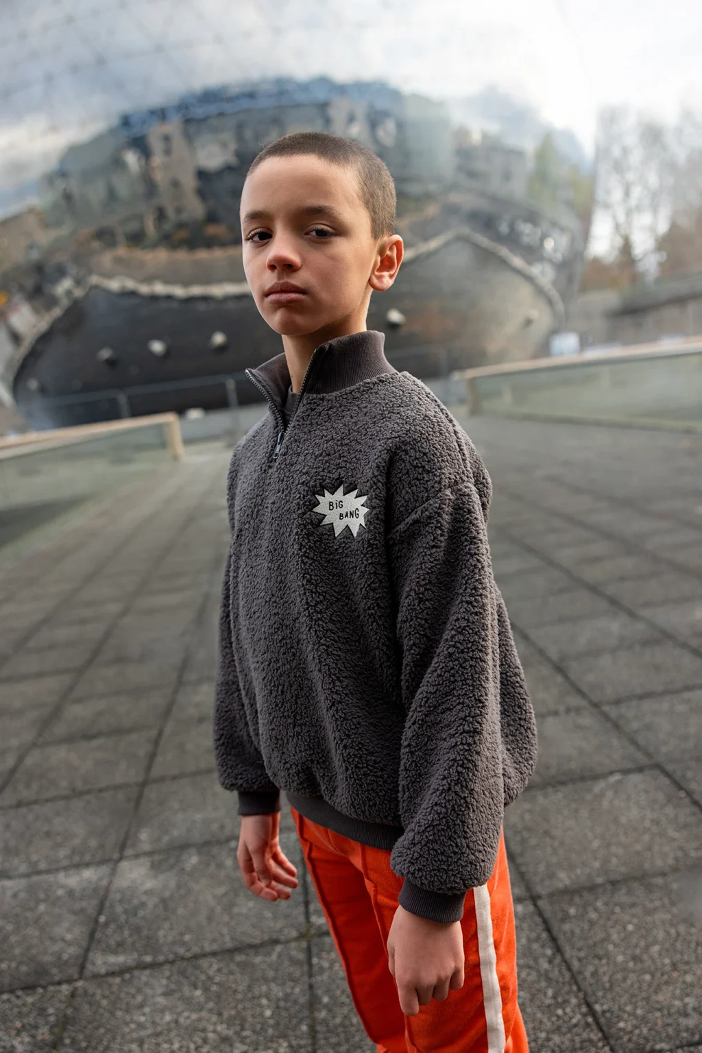 a group of kids standing in front of a large reflective sphere